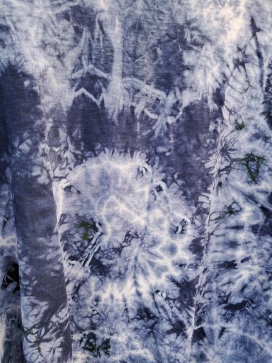 Blau-weißer Batikstoff mit spiralförmigen und strahlenartigen Mustern.