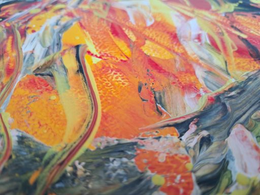 Bunte Farbsplash mit orange, gelb und grünen Akzenten auf strukturierter Oberfläche.